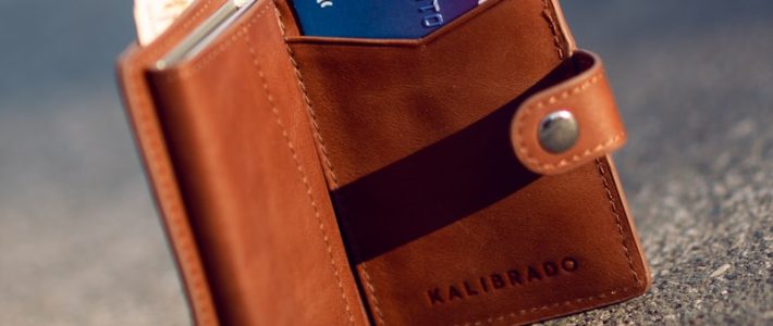 brown leather bifold wallet on gray concrete floor